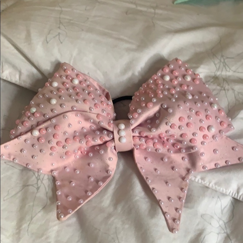 A pink cheer bow with pearls on it